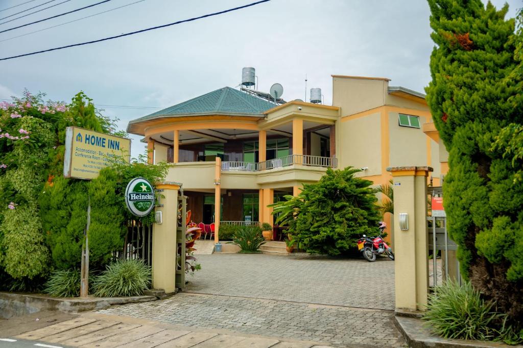 鲁亨盖里Home Inn Hotel Rwanda的前面有标志的大型黄色房屋