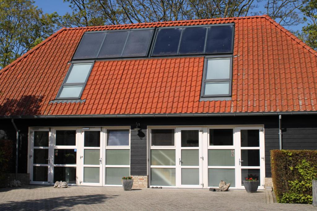 坎珀兰Hoeve Hofwijk的橙色屋顶建筑,设有白色门窗