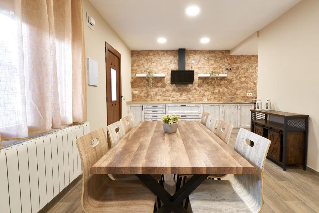 塞哥维亚Casa Rural El Paloteo的一间带木桌和椅子的用餐室