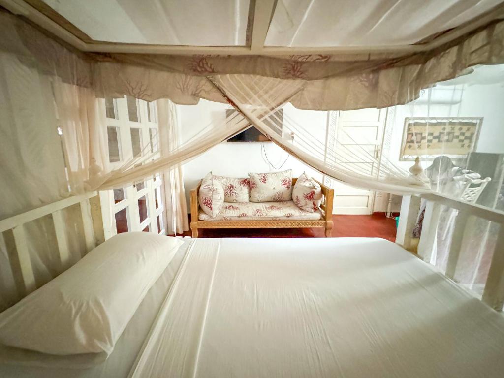 马林迪Kaleb's Serviced Beachfront Villa的卧室配有床、椅子和窗户。