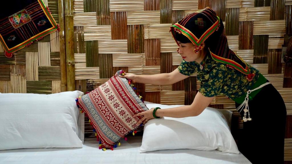 Ban Hin LomHomestay Minh Ngọc的站在床上的女人,拿着枕头