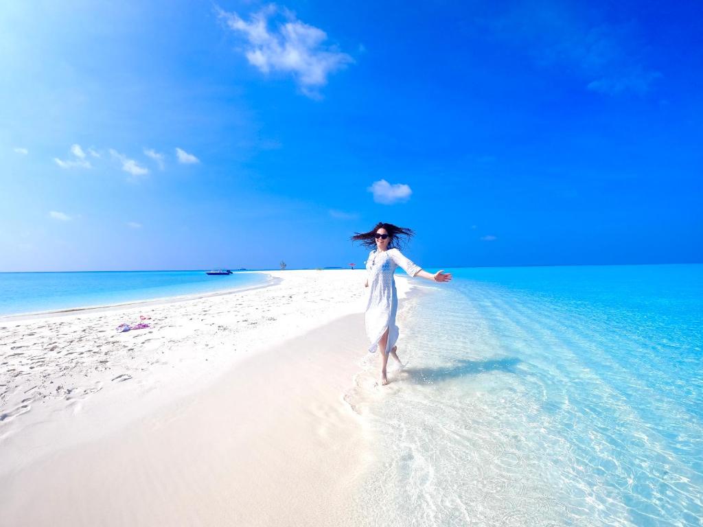 古雷德胡Wind Breeze Sunset View Inn的穿白色衣服的女人在海滩上散步