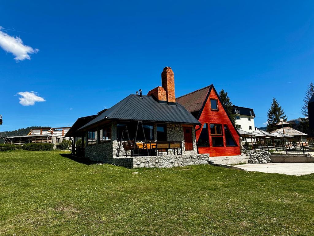 弗拉西克Holiday home Kraljica的绿色田野上黑色屋顶的红色房子