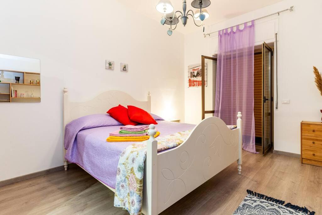 QuattromiglioGuestHouse Pet's Friendly的一间卧室配有一张带紫色床单和红色枕头的床。