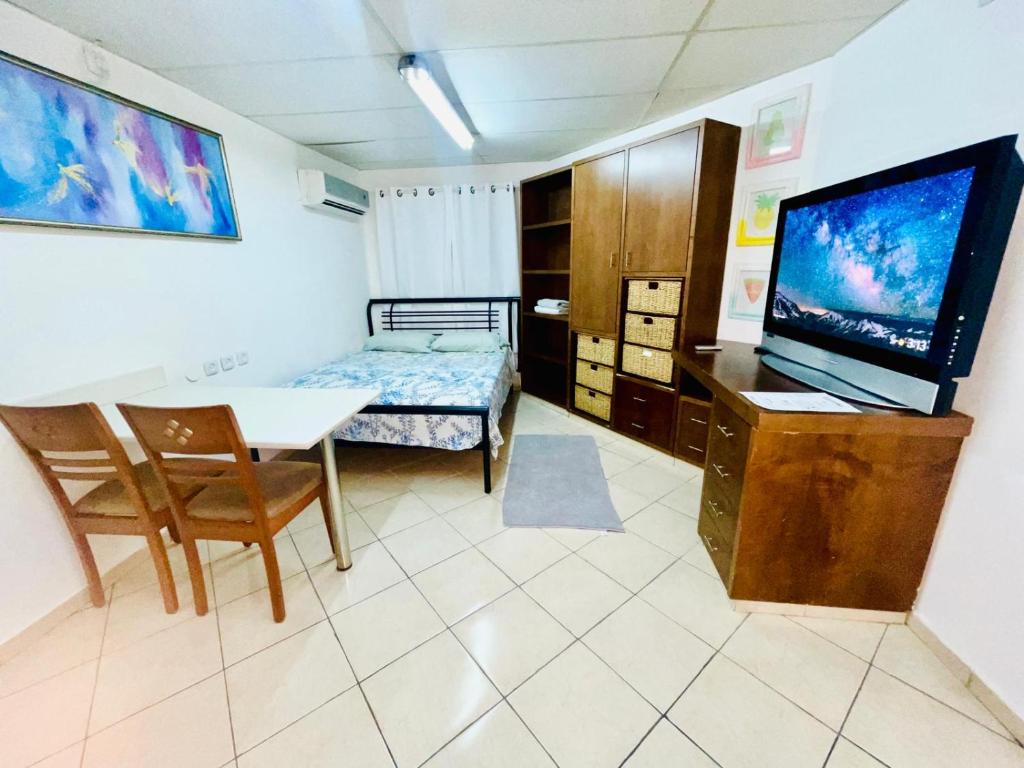埃拉特Eilat Beach House的一间设有桌子、床和电视的客房