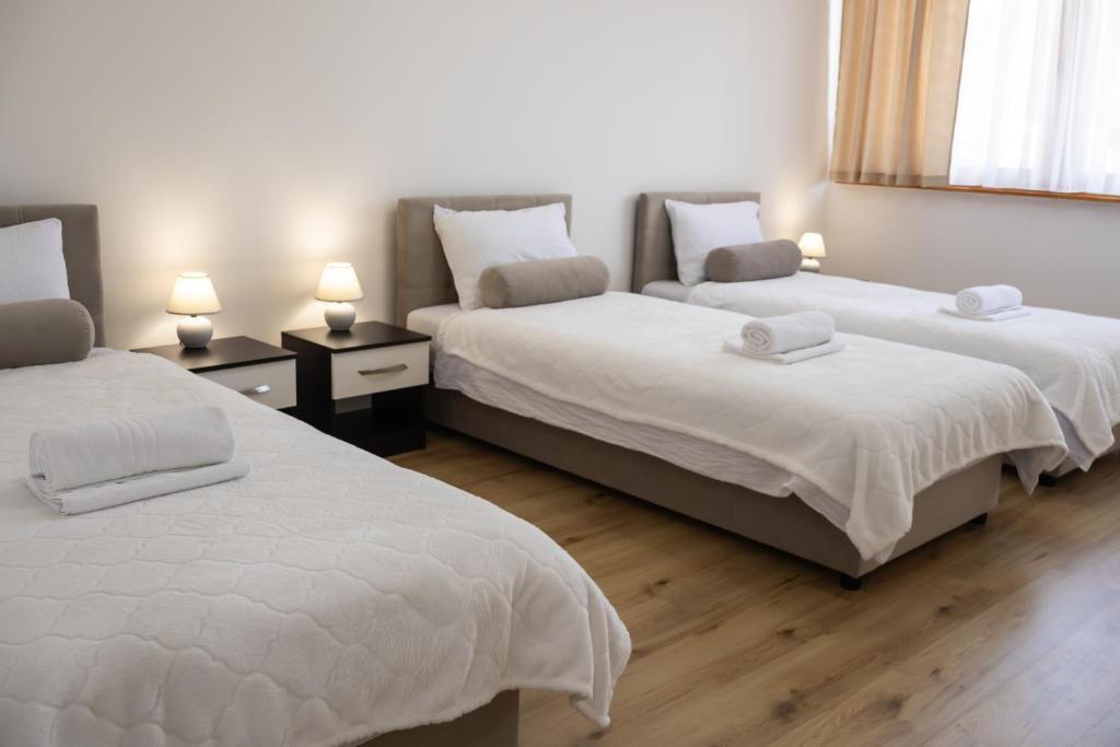 萨拉热窝Apartment Nanami的一间卧室配有两张带白色床单和灯具的床。