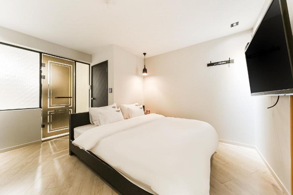 釜山2 Heaven Hotel Songdo的卧室配有白色的床和电视。