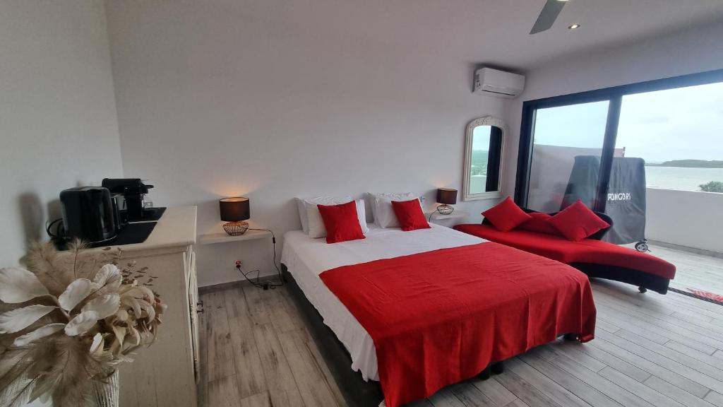 努美阿VUE SUR MER的一间卧室配有一张带红色枕头的大床