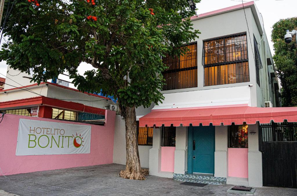 圣多明各Hotelito Bonito Eli & Edw的粉红色和白色的建筑,前面有树