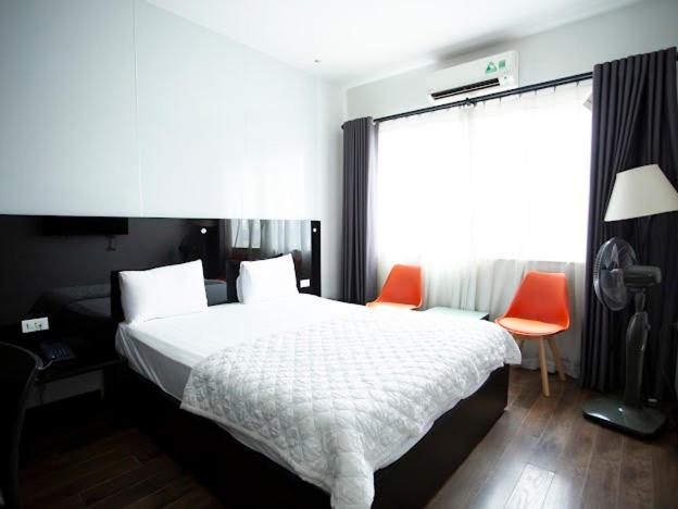 河内Ánh Hồng Hottel的一间卧室配有一张床和两张橙色椅子