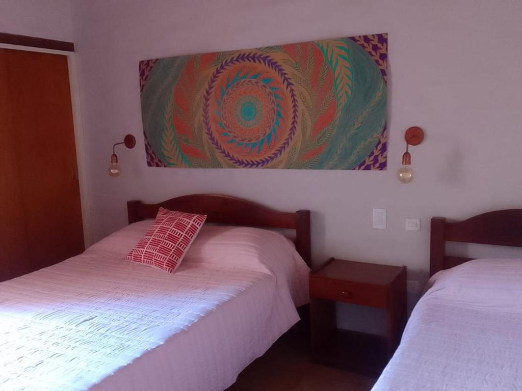 多洛雷斯镇Hotel Hualum的一间卧室设有两张床,墙上挂着一幅画