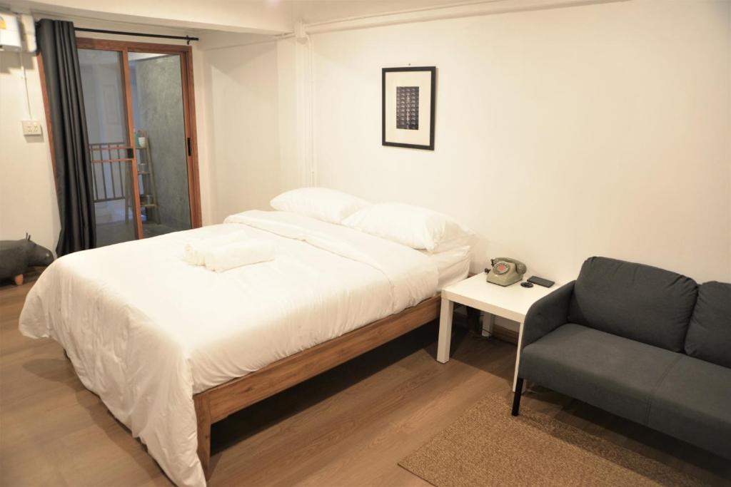 班敦孟BPP Resident near Donmueang Airport的一间卧室配有一张床、一张沙发和一把椅子