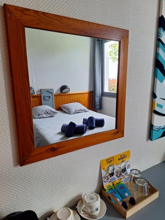 梅里尼亚克Escale Kennedy的卧室配有一张壁挂镜子的床
