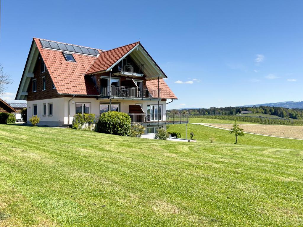 博登湖畔克雷斯波洛Ferienhof Lang的绿色田野上一座红色屋顶的房子
