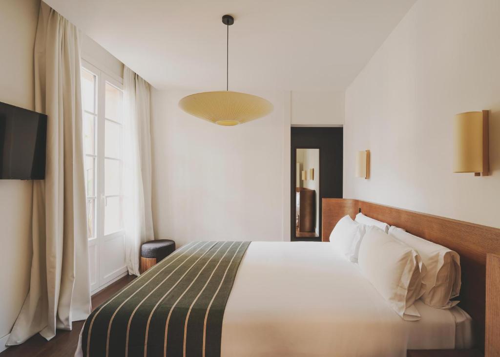 巴塞罗那Hotel Regina Barcelona的一间卧室设有一张床和一个大窗户