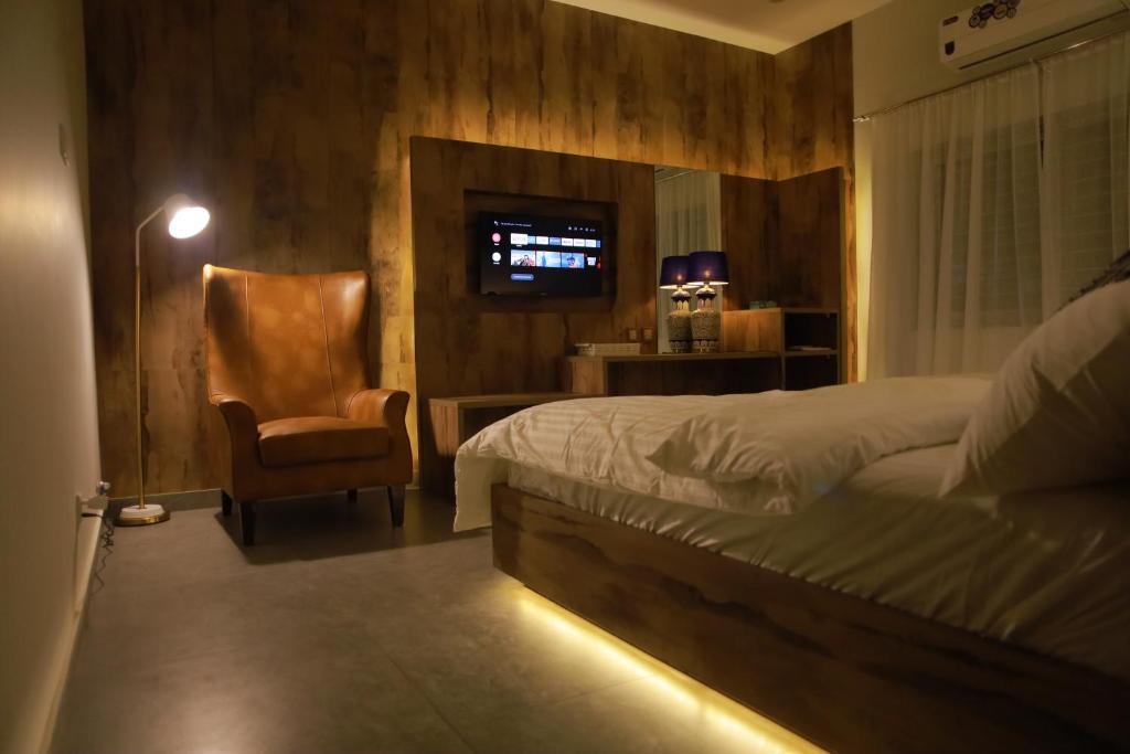 卡拉奇Sunset BnB的一间卧室配有一张床、一把椅子和电视