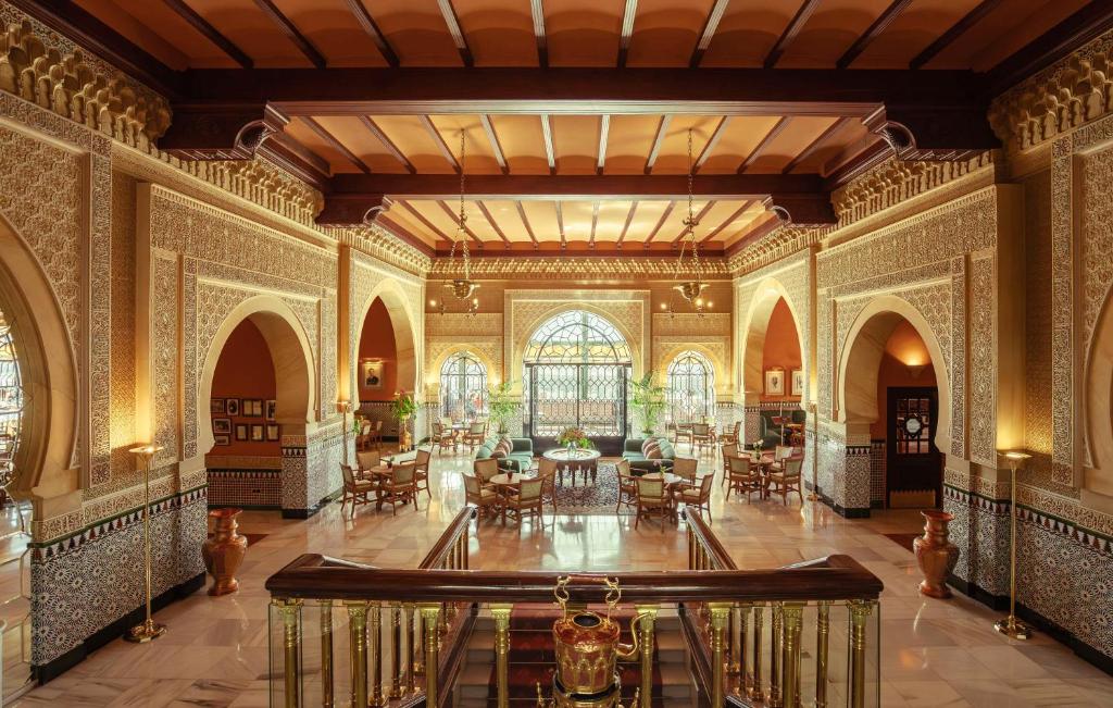 格拉纳达Alhambra Palace Hotel的大楼内带桌椅的华丽客房