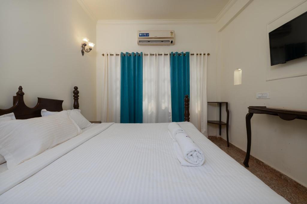 阿姆波尔Feliz Arambol的卧室配有一张带蓝色窗帘的大型白色床