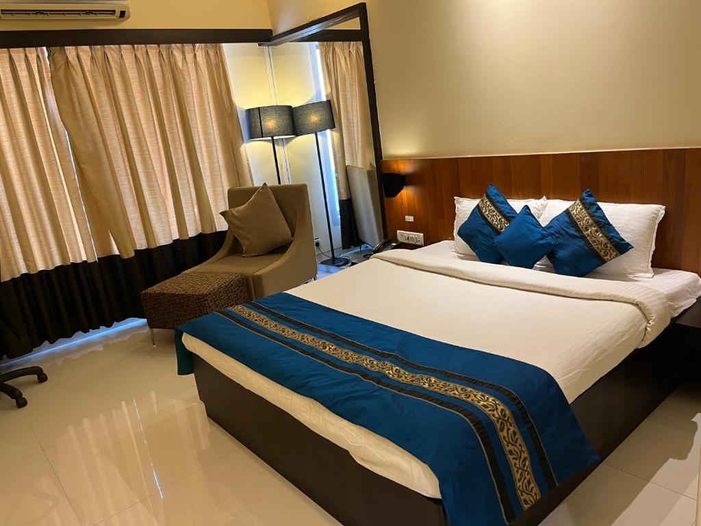 拉特纳吉里Hotel Landmark Ratnagiri的酒店客房带一张大床和一把椅子