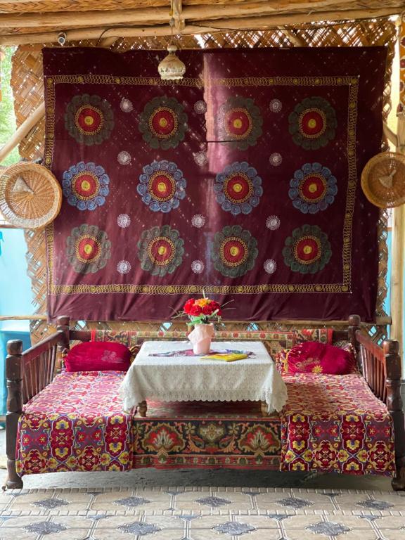 费尔干纳Sohil boyi的一张带桌子的床,上面有花瓶