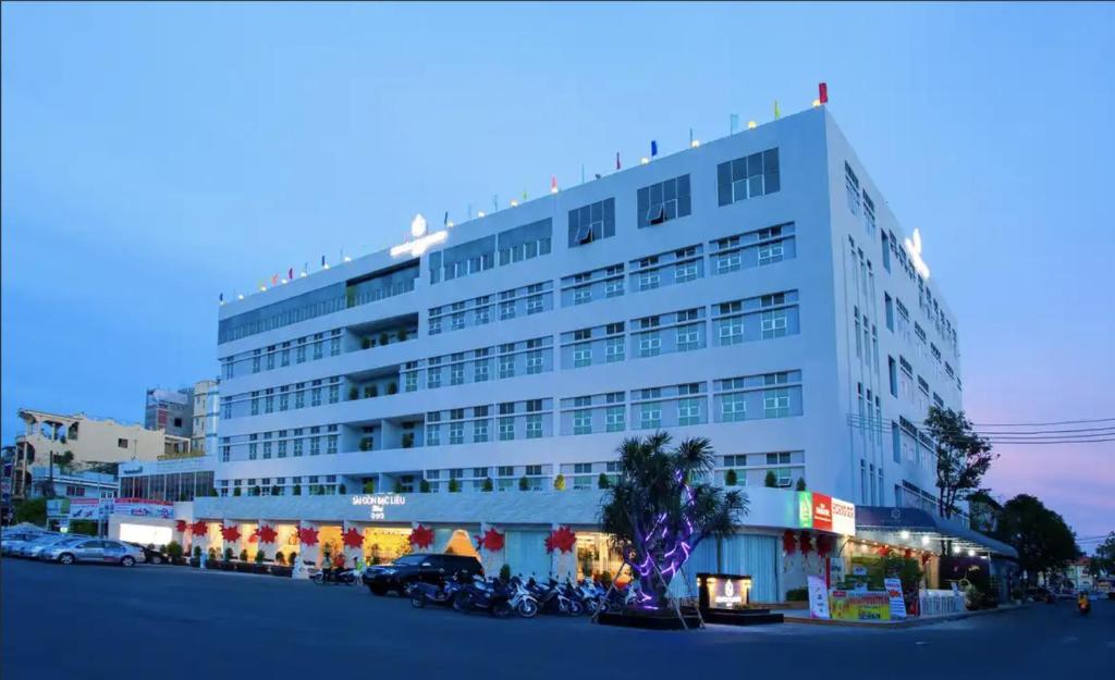 Bạc LiêuSÀI GÒN - BẠC LIÊU Hotel的一座大型白色建筑,前面停有摩托车