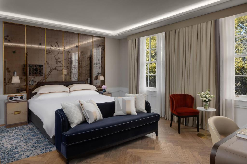 伦敦The Biltmore Mayfair的一间卧室配有一张大床和一张蓝色的沙发