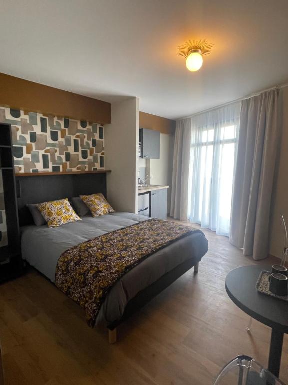 勒阿弗尔Smart Appart Le Havre 105的一间卧室配有一张床、一张桌子和一个窗户。