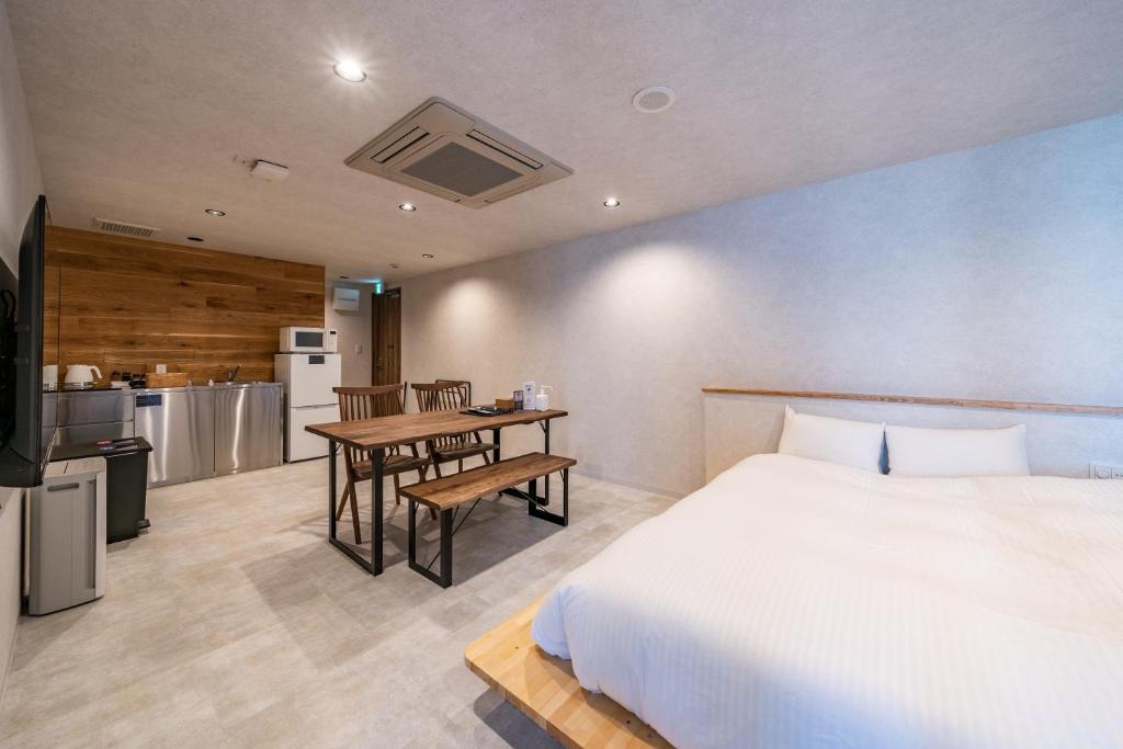 高山Relax Hotel Takayama Station的一间卧室配有一张床铺和一张桌子,还设有一间厨房