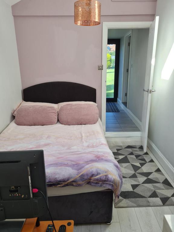 哈洛1 Bed Annex 2 mins from Harlow Mill train station的一间卧室配有一张带粉红色枕头的床和一张桌子