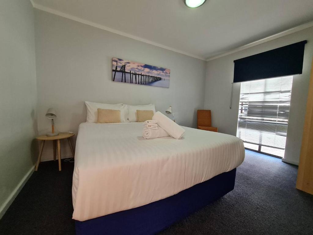 珀斯West Beach Lagoon 204 - Ground Floor!的卧室设有一张白色大床和一扇窗户。