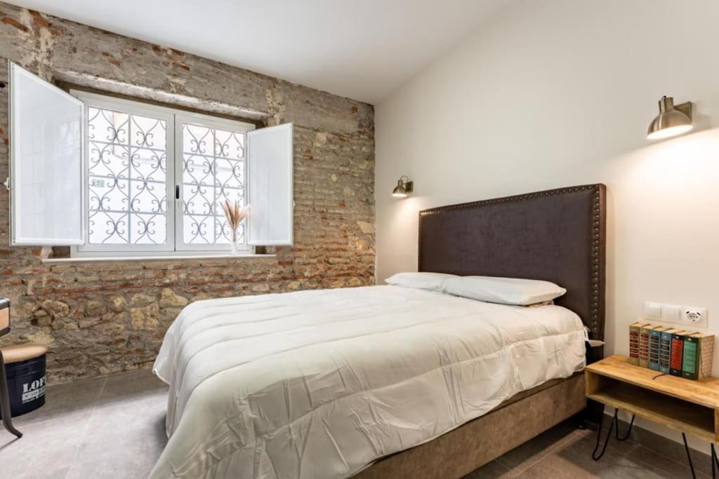 阿尔么丽亚Estrena Apartamento en centro historico de Almeria的一间卧室设有一张大床和砖墙