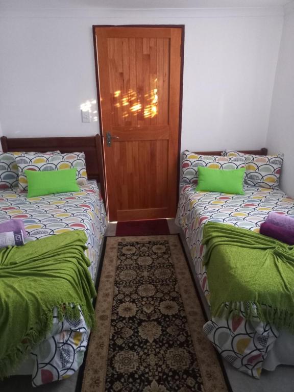波罗瓜尼Eloff's Guest House的配有绿色枕头和门的客房内的两张床