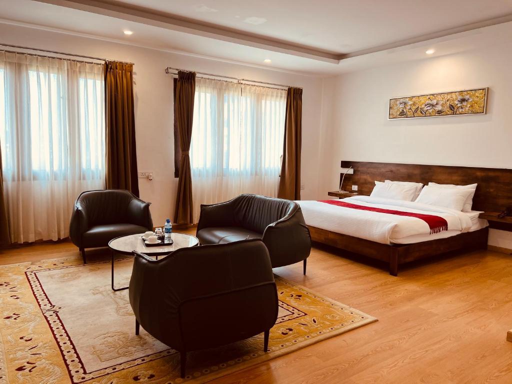 廷布Hotel Mayto的酒店客房带一张床、一张桌子和椅子