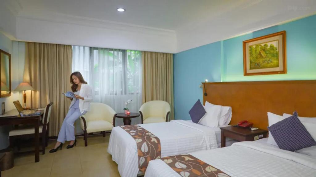 雅加达Stay 'd Kuningan的一名妇女站在带两张床的酒店房间