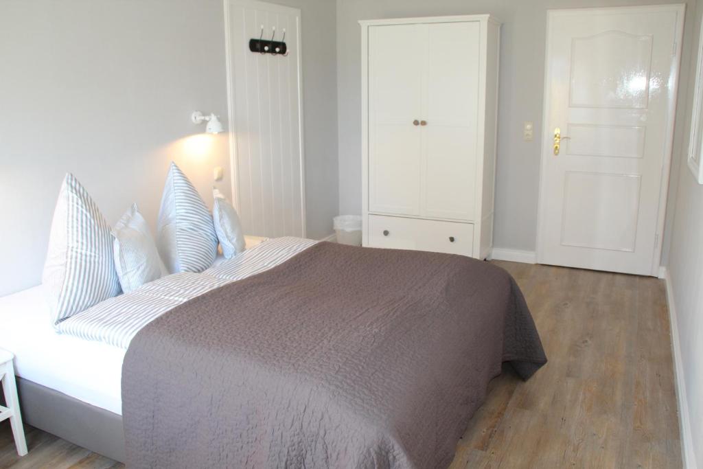 UtersumLandhaus Nordstern Hotel garni的白色卧室配有一张带蓝色枕头的大床