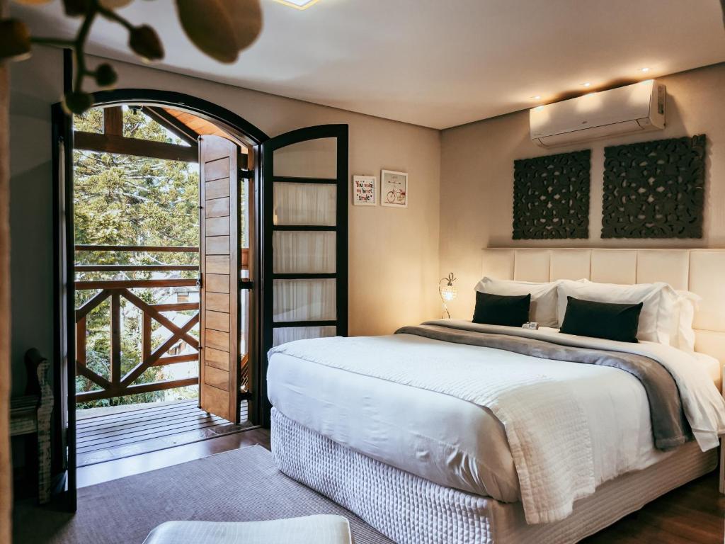 蒙特韦尔迪Hotel Harmonia Monte Verde的一间卧室设有一张床和一个大窗户