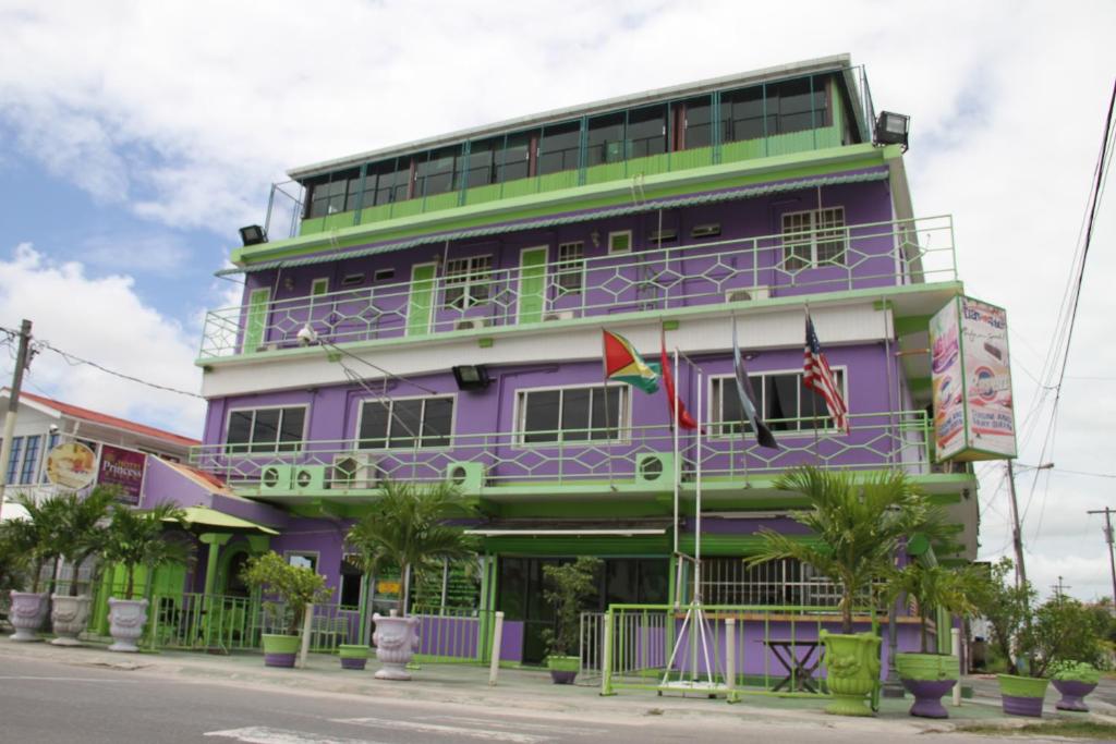 乔治敦PG Quality Inn的一座紫色绿色建筑,前面有棕榈树