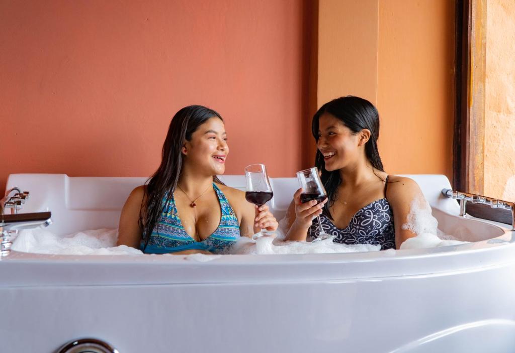 奥塔瓦洛Campo Lago Hospedaje的两个女人坐在浴缸里,拿着酒杯