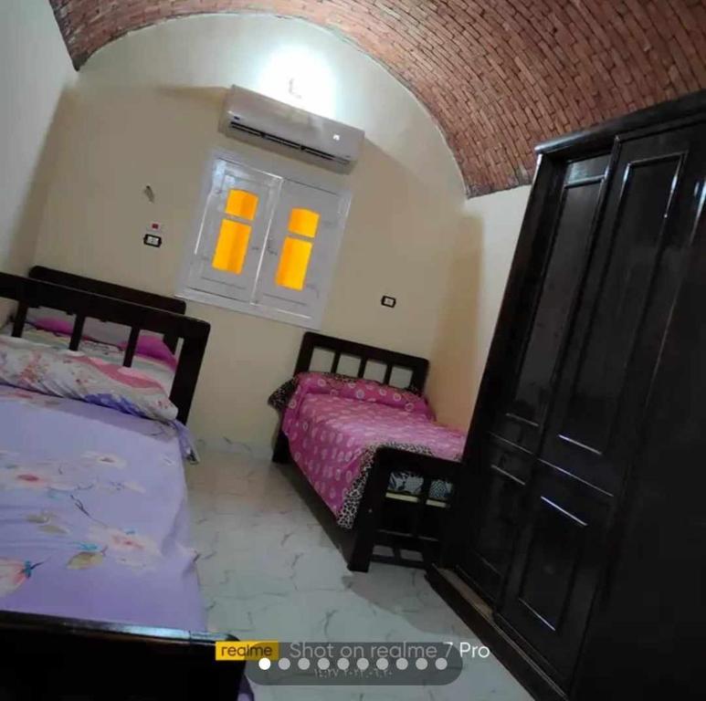 阿斯旺Aswan Fully furnished apartment اسوان- امتداد العقاد的一间卧室设有两张床,窗户拥有黄色的灯光。