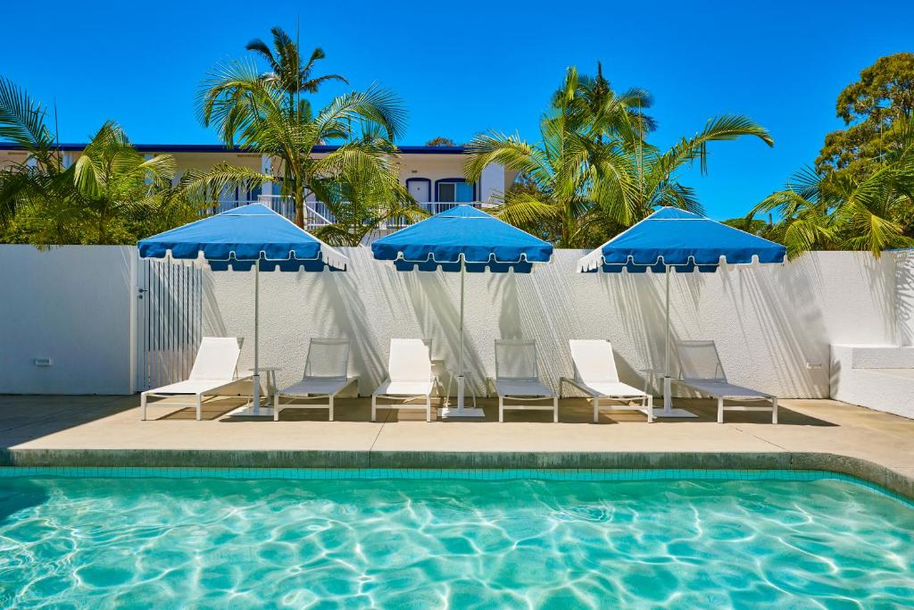 布伦瑞克黑兹不伦瑞克海兹帆船汽车旅馆的一组椅子和遮阳伞,位于游泳池旁
