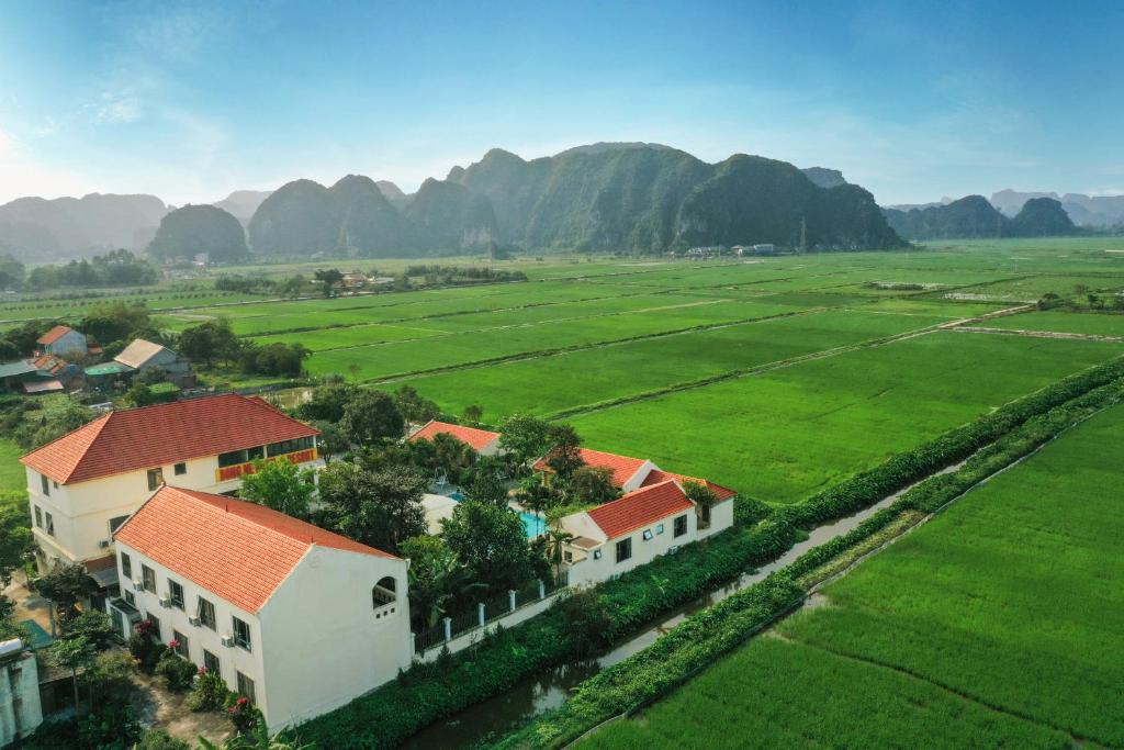 宁平Dong Ne Tam Coc Hotel & Resort的享有村庄的空中景色,以群山为背景