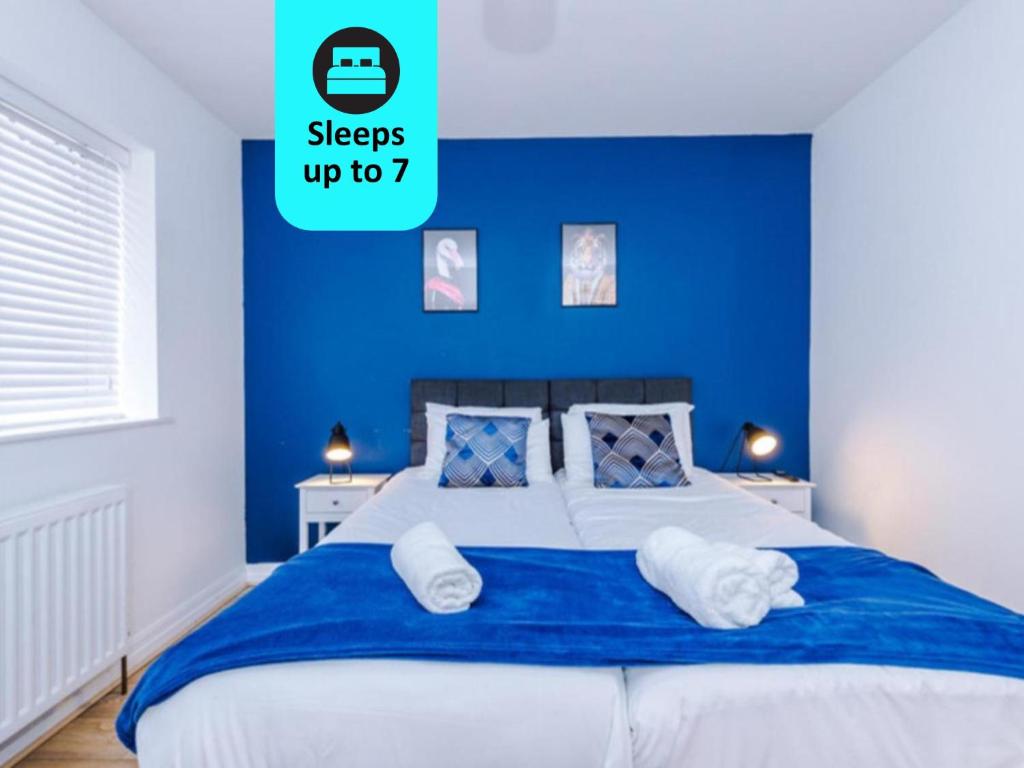 曼彻斯特Lovely 3 Bed house - Park Lane的一间卧室拥有蓝色的墙壁,配有一张带枕头的床。