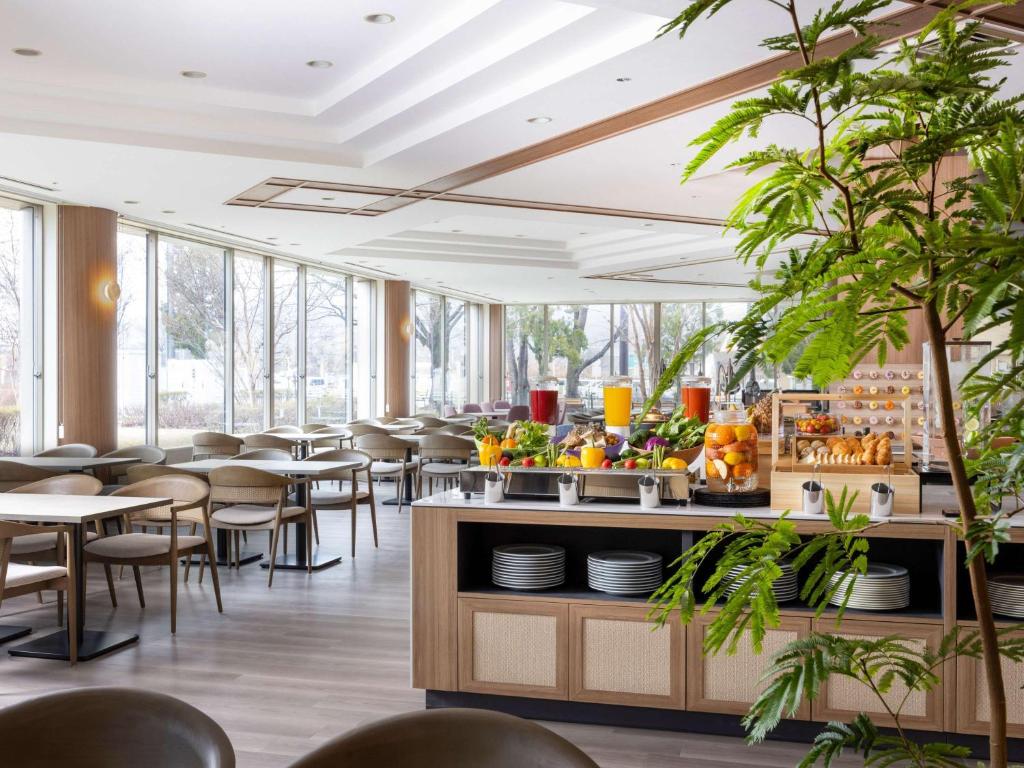长野Mercure Nagano Matsushiro Resort & Spa的用餐室设有桌椅和窗户。