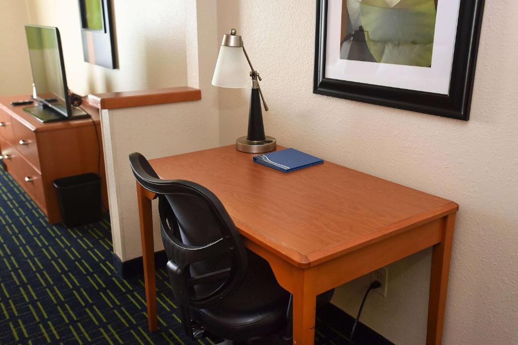 托皮卡AmericInn by Wyndham Topeka的一张桌子,位于酒店的房间,配有一盏灯和一把椅子