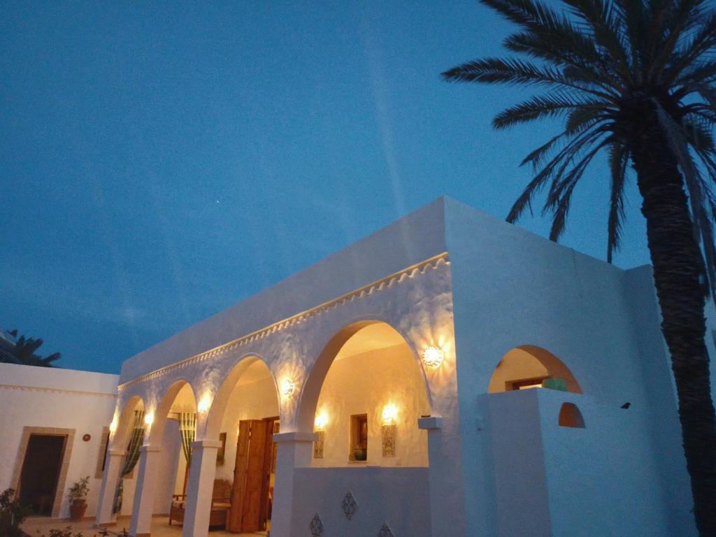米多恩Djerba Rêve Vacances Emna EL Beya的一座白色的建筑,旁边是棕榈树