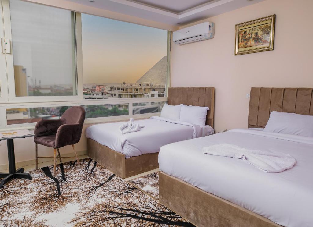开罗Mak Pyramids View的酒店客房设有两张床、一张书桌和一个窗户。