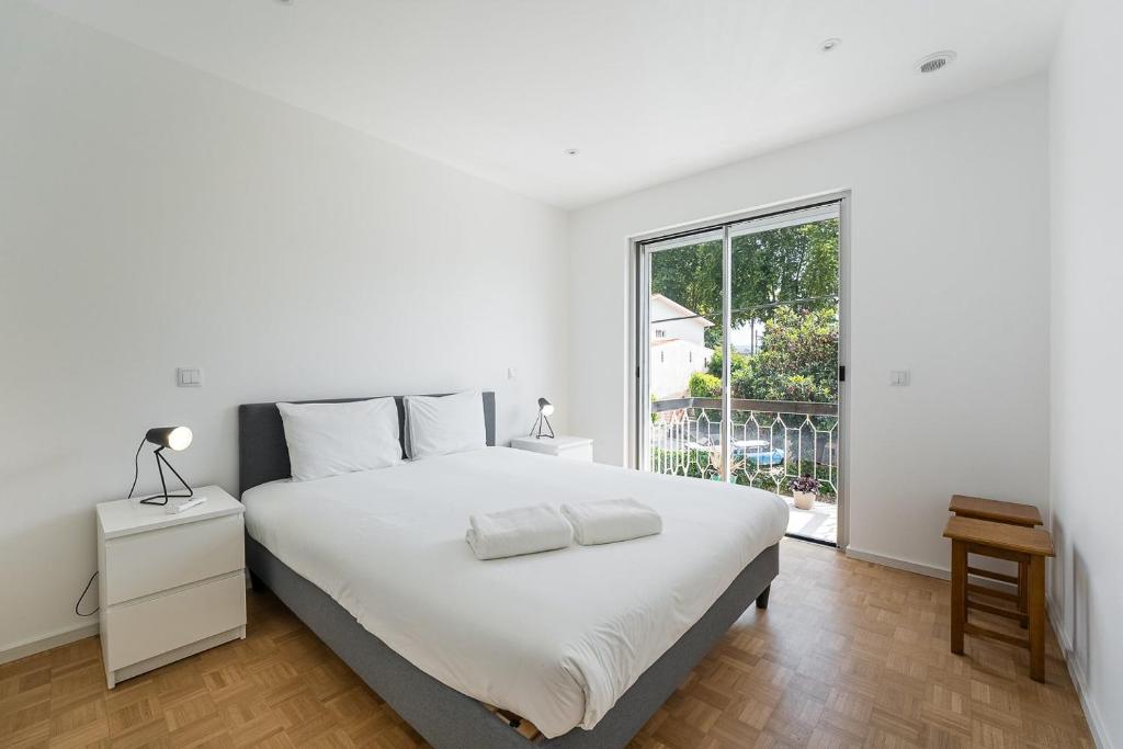 里奥廷托GuestReady - Relaxing stay in Rio Tinto的白色的卧室设有一张大床和一个窗户