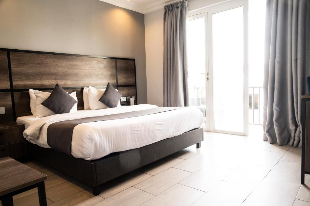 拉各斯河豚酒店的一间卧室配有一张大床和木制床头板