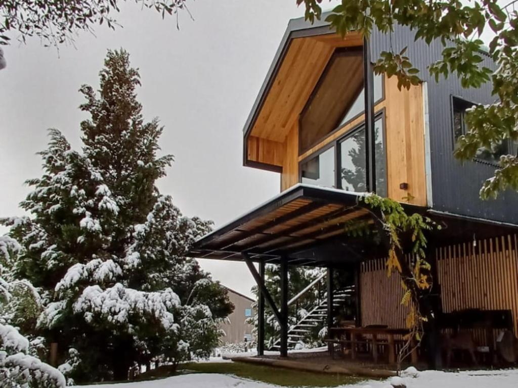 圣马丁德洛斯Casa de montaña La Cumba Patagonia.的雪中带木屋顶的房子