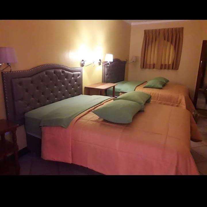 阿亚库乔HOSPEDAJE KAROL的酒店客房设有两张床和一张桌子。